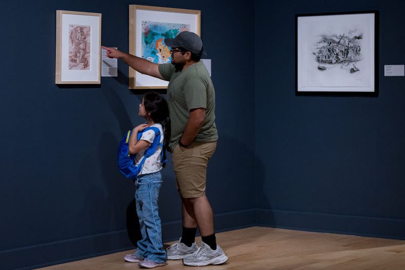 Josue Juarez-Gonzalez points out a work of art to his daughter, Astraea Juarez-Gonzalez, in the El Paso Museum of Art's newest exhibition, "America, The Beautiful: Selections from the Zoe Diaz Collection," on Saturday, July 25, 2026.