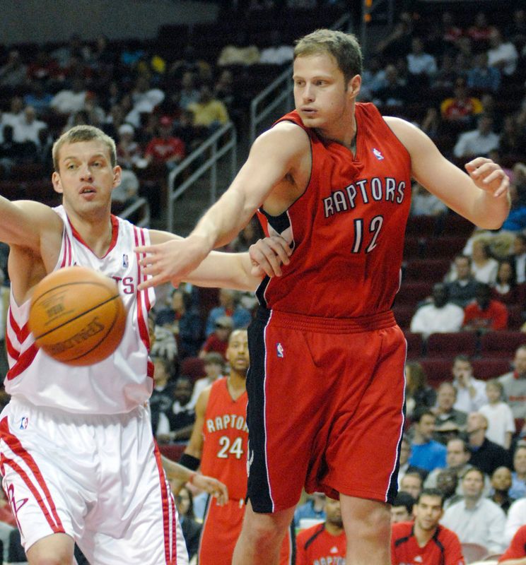 The Toronto Raptors' Rasho Nesterovic (12) from Slovenia passes the ball back past the Houston Rockets' Jake Tsakalidis in the first quarter of their NBA basketball game in Houston February 28, 2007.  REUTERS/Tim Johnson  (UNITED STATES)