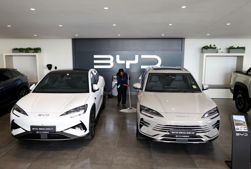 FILE PHOTO: Amukelani Masungi, a worker, cleans the floor next to BYD vehicles on display at a BYD dealership in Sandton, South Africa, June 5, 2025. REUTERS/Siphiwe Sibeko/File Photo