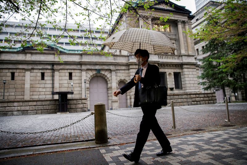 FILE PHOTO: FILE PHOTO: An office employee walks in front of the bank of Japan building in Tokyo, Japan, April 7, 2023. REUTERS/Androniki Christodoulou/File Photo/File Photo
