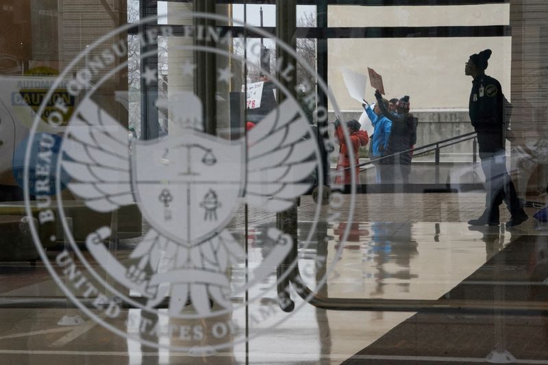 FILE PHOTO: A special police member monitors a protest, while inside the Consumer Financial Protection Bureau (CFPB) building, the day after members of Elon Musk's Department of Government Efficiency (DOGE) moved into the CFPB, in Washington, U.S. February 8, 2025. REUTERS/Nathan Howard/File Photo