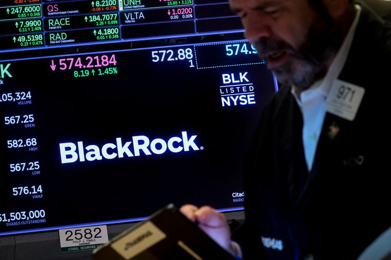FILE PHOTO: A trader works as a screen displays the trading information for BlackRock on the floor of the New York Stock Exchange (NYSE) in New York City, U.S., October 14, 2022. REUTERS/Brendan McDermid/File Photo