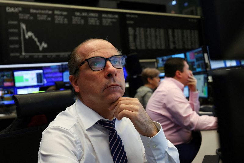 A stock broker looks at his screens in front of the share price index DAX graph following the shares of Credit Suisse hit a record low in a rout of European bank stocks, as investor concerns about sector stresses triggered by Silicon Valley Bank's implosion deepened, at the stock exchange in Frankfurt, Germany, March 16, 2023. REUTERS/Kai Pfaffenbach/File Photo