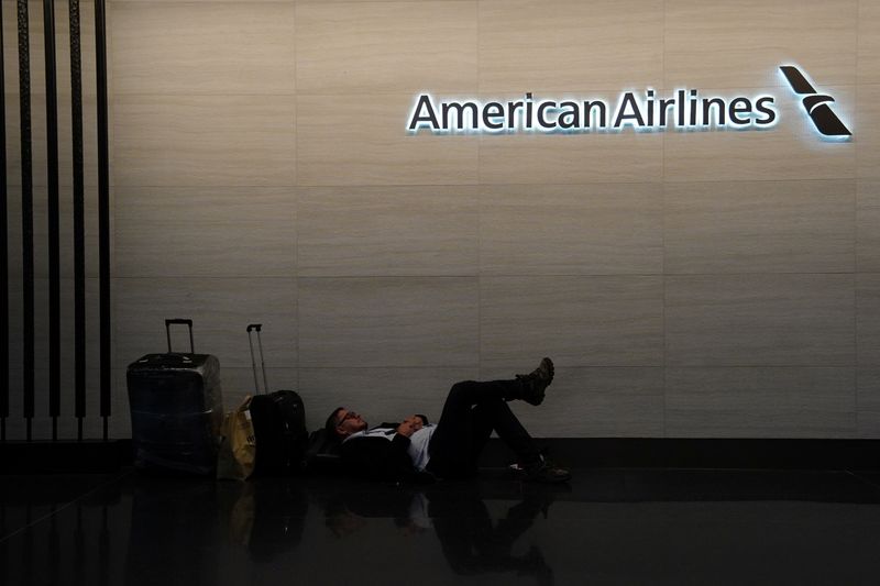 FILE PHOTO: A traveler sleeps near the American Airlines check-in area at Terminal 8 at John F. Kennedy International Airport, in New York, U.S., June 8, 2025. REUTERS/Bing Guan/File Photo