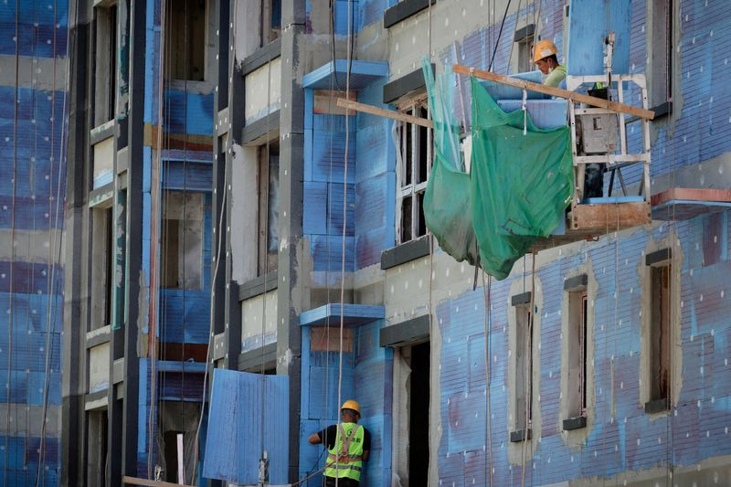 FILE PHOTO: Men work at a construction site for apartment buildings in Beijing, China, July 15, 2022. REUTERS/Thomas Peter/File Photo