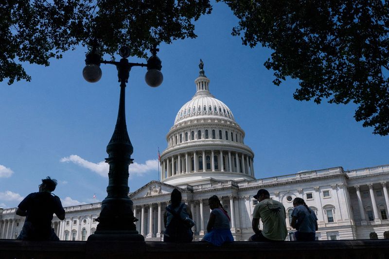 FILE PHOTO: Visitors to the U.S. Capitol rest in the shade on Capitol Hill in Washington, D.C., U.S., June 25, 2025. REUTERS/Nathan Howard/File Photo