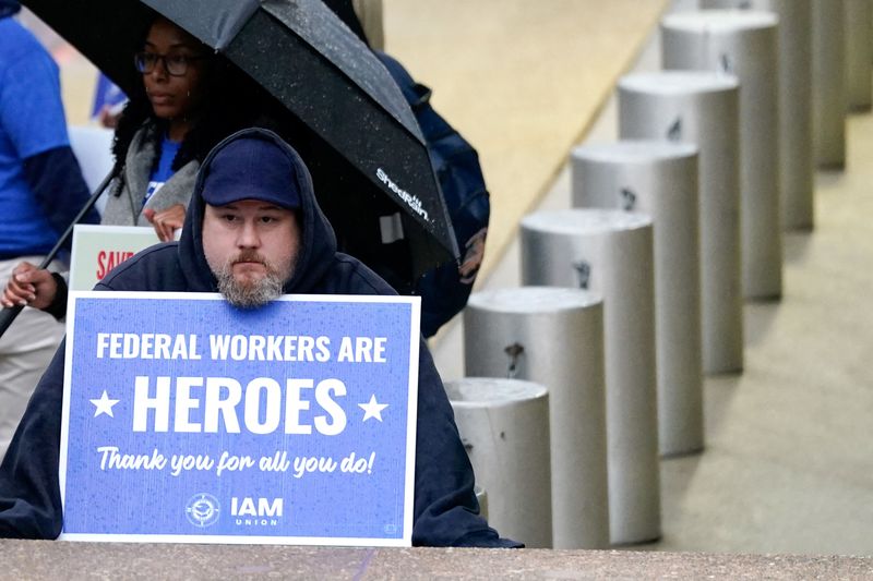FILE PHOTO: A labor union members holds a placard on the day of a rally in support of federal workers during a rush hour protest outside the L'Enfant Plaza Metro Station in Washington, D.C., U.S., March 24, 2025. REUTERS/Kent Nishimura/File Photo