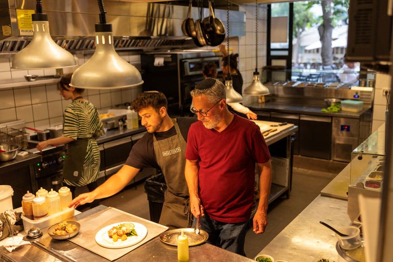 Tzvi Maller, the owner of MOJO's Bistro, is seen inside the restaurant kitchen during service, in Jerusalem, July 1, 2025. REUTERS/Ronen Zvulun