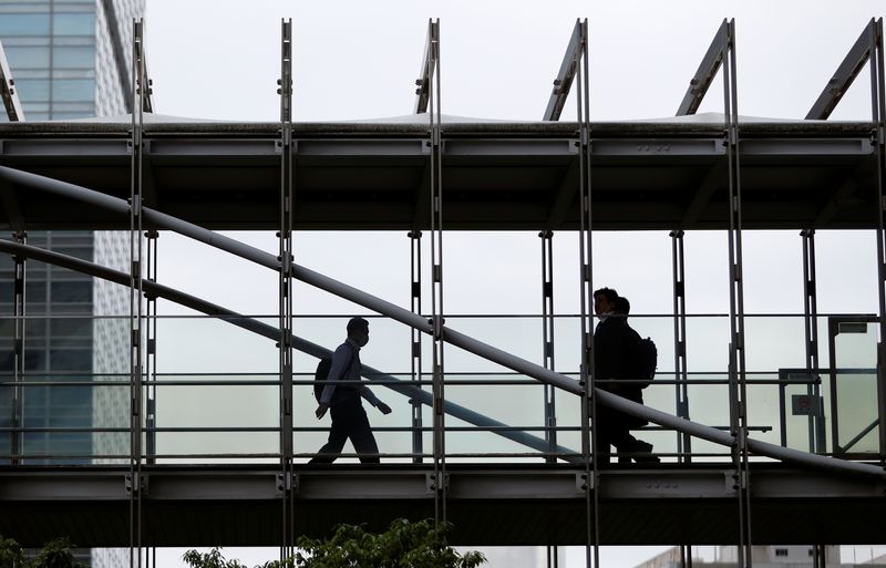 FILE PHOTO: Businessmen wearing protective face masks walk on a pedestrian bridge in a business district in Tokyo, Japan June 24, 2020. REUTERS/Issei Kato/ File Photo