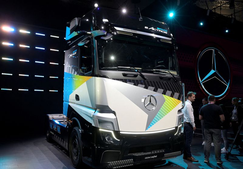FILE PHOTO: Members of the media stand beside an electric driven Actros truck at the booth of German truckmaker Daimler Truck at the IAA Transportation fair, which will open its doors to the public on September 20, 2022, in Hanover, Germany, September 19, 2022. REUTERS/Fabian Bimmer/File Photo