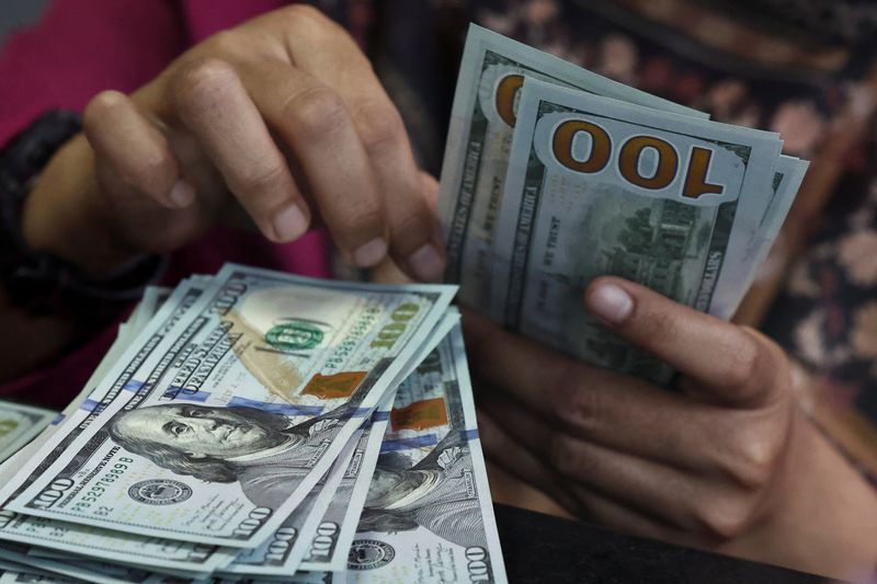 FILE PHOTO: A teller counts U.S. dollar bank notes at a money changer in Jakarta, Indonesia, April 9, 2025. Picture taken through glass. REUTERS/Willy Kurniawan/ File Photo