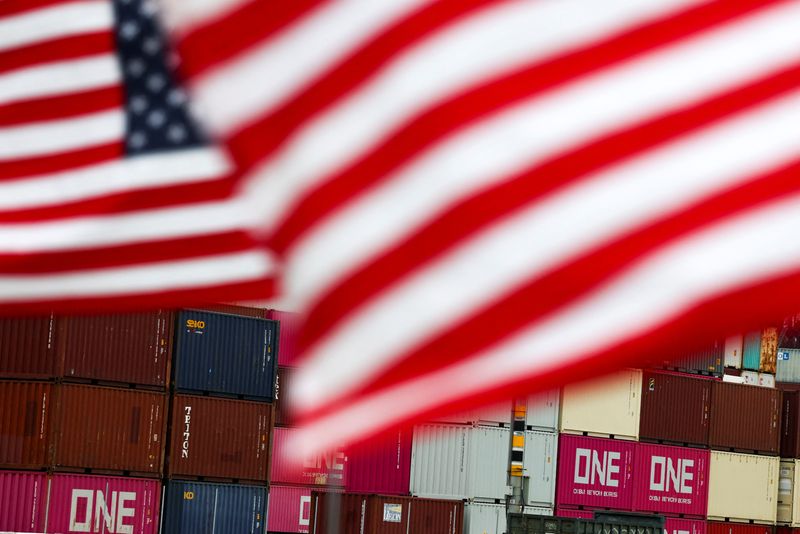 FILE PHOTO: U.S. flags flutter in front of shipping containers at the Port of Long Beach in Long Beach, California, U.S., July 11, 2025. REUTERS/Daniel Cole/ File Photo