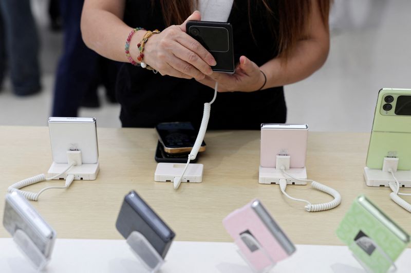 FILE PHOTO: A woman checks a Huawei Nova Flip foldable smartphone displayed at a Huawei flagship store, near an Apple store in Beijing, China September 10, 2024. REUTERS/Florence Lo/File Photo