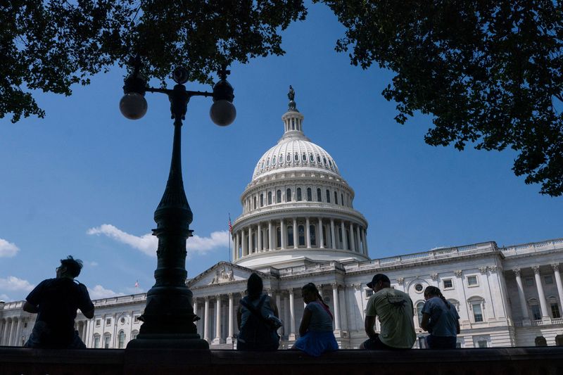 FILE PHOTO: Visitors to the U.S. Capitol rest in the shade on Capitol Hill in Washington, D.C., U.S., June 25, 2025. REUTERS/Nathan Howard/ File Photo