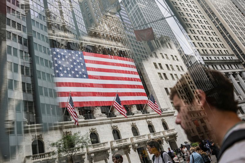 FILE PHOTO: People walk past the New York Stock Exchange (NYSE) in New York City, U.S., July 11, 2025. Picture taken through glass. REUTERS/Jeenah Moon/ File Photo