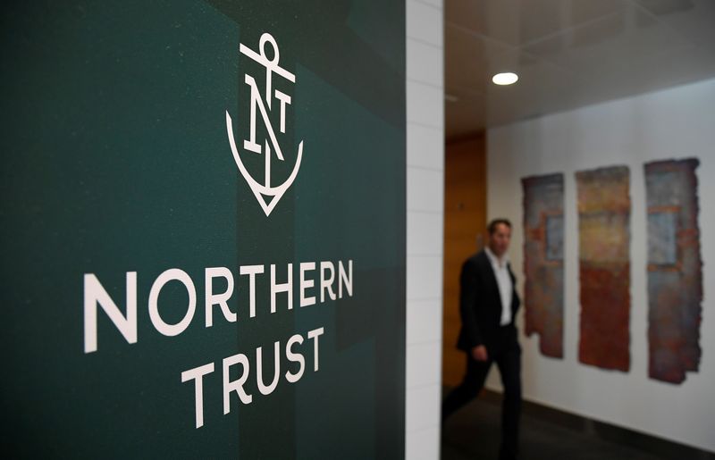 FILE PHOTO: An employee walks past a company logo at Northern Trust offices in London, Britain August 1, 2019. Picture taken August 1, 2019. REUTERS/Toby Melville/FIle photo
