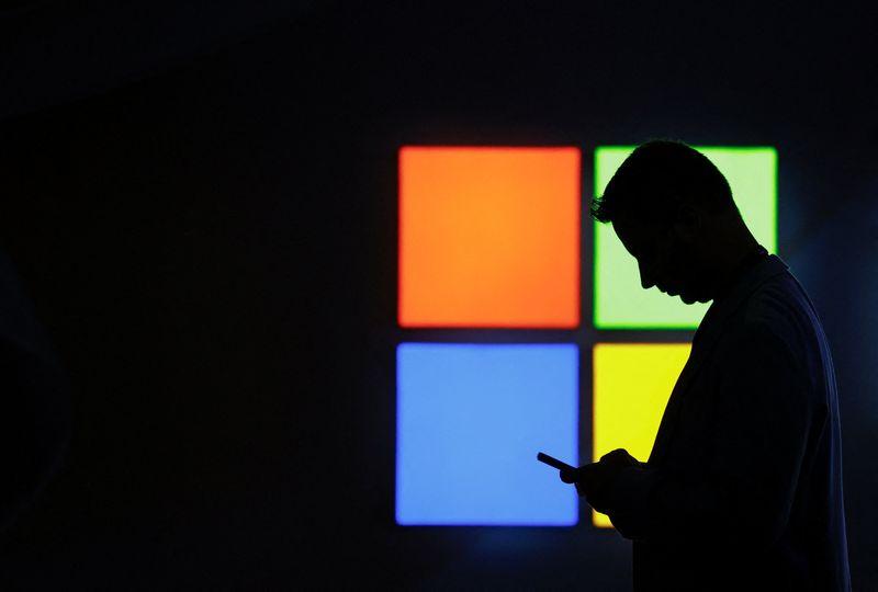 A man looks at his phone as he passes by the Microsoft stand at the Mobile World Congress trade show, in Barcelona, Spain, March 3, 2025. REUTERS/Bruna Casas
