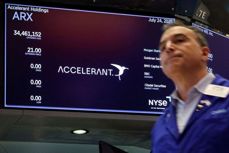 A trader walks by a screen showing the company logo and trading information for insurance marketplace Accelerant during the company's IPO at the New York Stock Exchange (NYSE) in New York City, U.S., July 24, 2025. REUTERS/Brendan McDermid