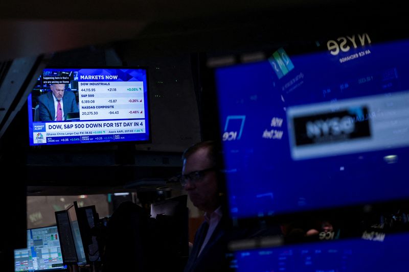 FILE PHOTO: A screen displays news on DOW and S&P 500 stock market indices, as traders work on the floor at the New York Stock Exchange (NYSE) in New York City, U.S., July 1, 2025. REUTERS/Jeenah Moon/File Photo