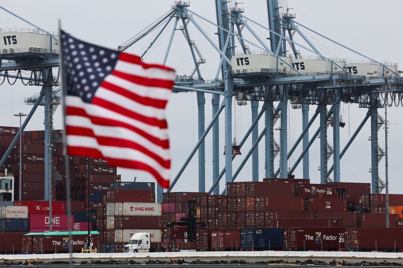 FILE PHOTO: A U.S. flag flutters in front of shipping containers at the Port of Long Beach in Long Beach, California, U.S., July 11, 2025. REUTERS/Daniel Cole/File photo