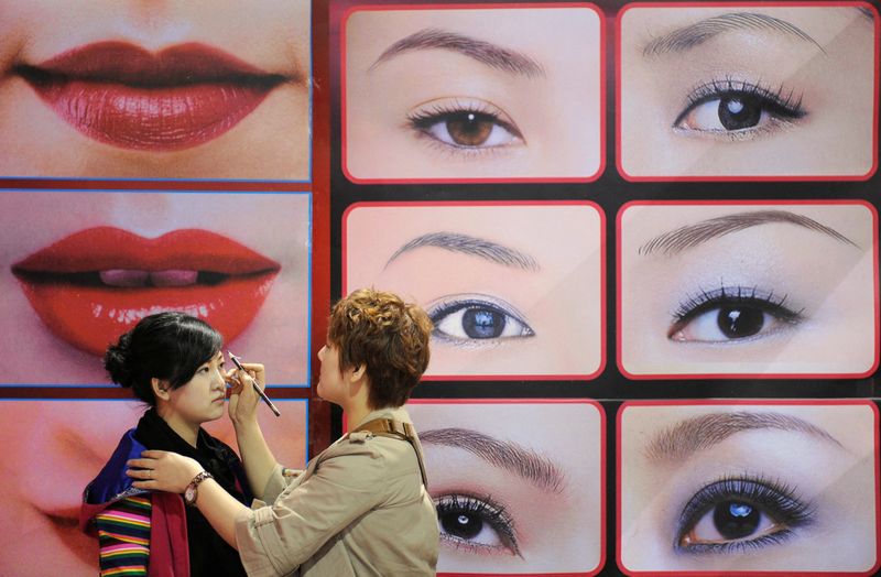 FILE PHOTO: A beautician puts on make-up for a model in front of an advertisement at a beauty and hairdressing expo in Taiyuan in China's Shanxi province April 6, 2009. REUTERS/Stringer  CHINA OUT. NO COMMERCIAL OR EDITORIAL SALES IN CHINA/File Photo