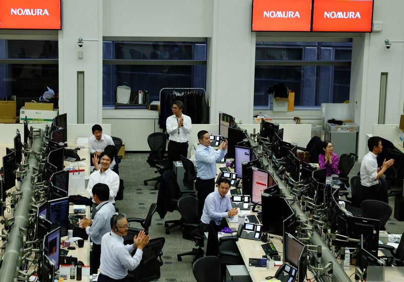 FILE PHOTO: Traders clap as the Nikkei index closes at an all-time high, at the dealing room of Nomura Securities in Tokyo, Japan, August 12, 2025. REUTERS/Kim Kyung-Hoon/File Photo