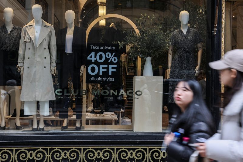 FILE PHOTO: People walk past a sale sign displayed on a retail store window, in Manhattan in New York City, U.S.,  February 25, 2025. REUTERS/Jeenah Moon/File Photo