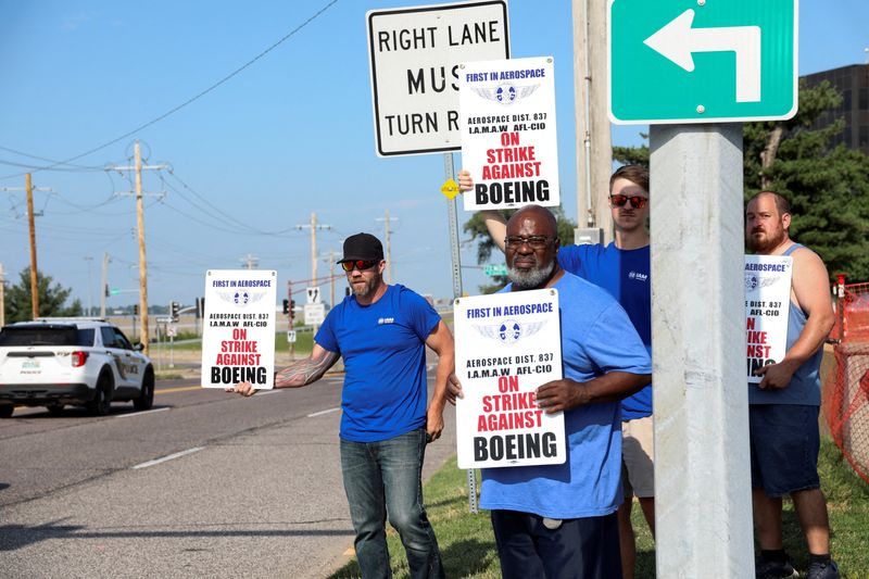 FILE PHOTO: Workers hold signs during a walkout by members of the International Association of Machinists and Aerospace Workers (IAM) over contract negotiations, outside Boeing company's facility, in Berkeley, Missouri, U.S., August 4, 2025. REUTERS/Lawrence Bryant/File Photo
