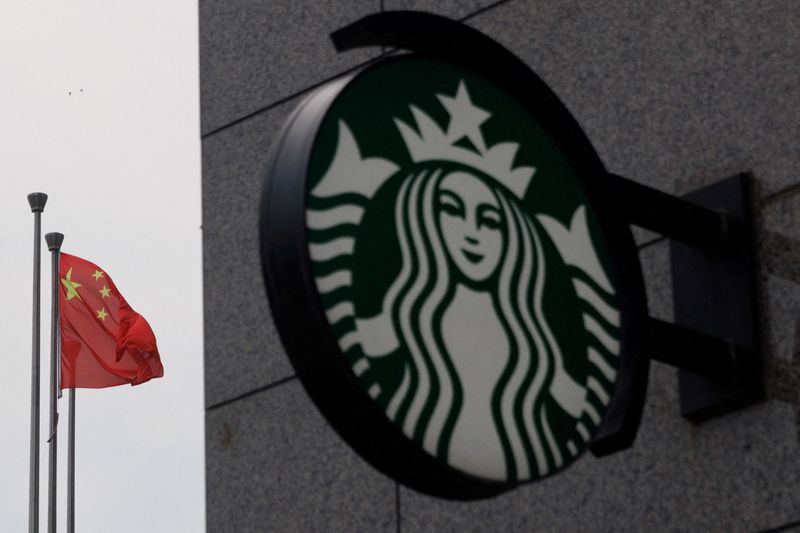 FILE PHOTO: The Chinese flag flies near the Starbucks logo outside a cafe of the coffee chain in Beijing, China, August 3, 2022. REUTERS/Thomas Peter/File Photo