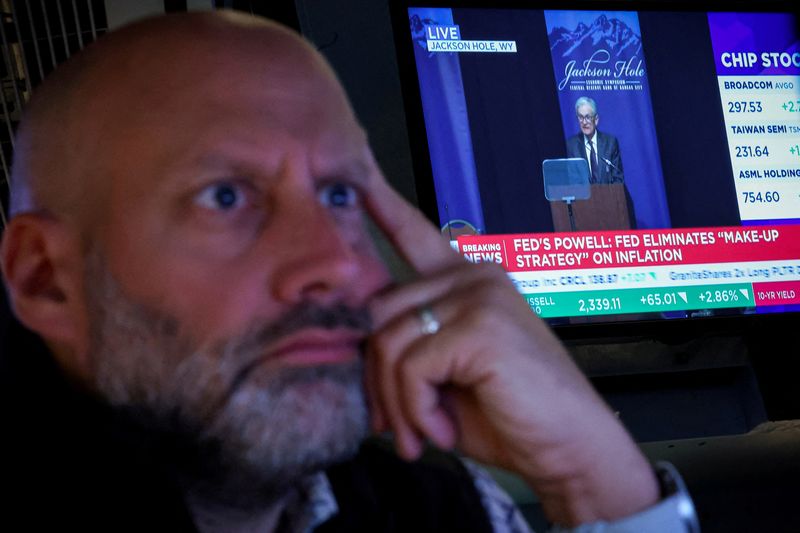 FILE PHOTO: A specialist trader works on the floor at the New York Stock Exchange (NYSE), as a screen shows Federal Reserve Chairman Jerome Powell speaking during the Jackson Hole conference, in New York City, U.S., August 22, 2025.  REUTERS/Brendan McDermid/File Photo