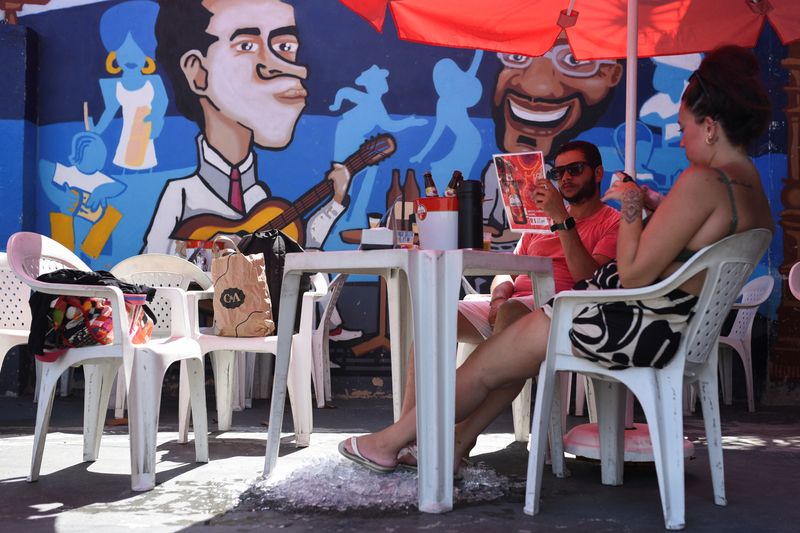 Customers place their feet on ice at a bar as restaurants undertake measures to mitigate the heat, amid high temperatures, in Rio de Janeiro, Brazil, January 25, 2025. REUTERS/Tita Barros