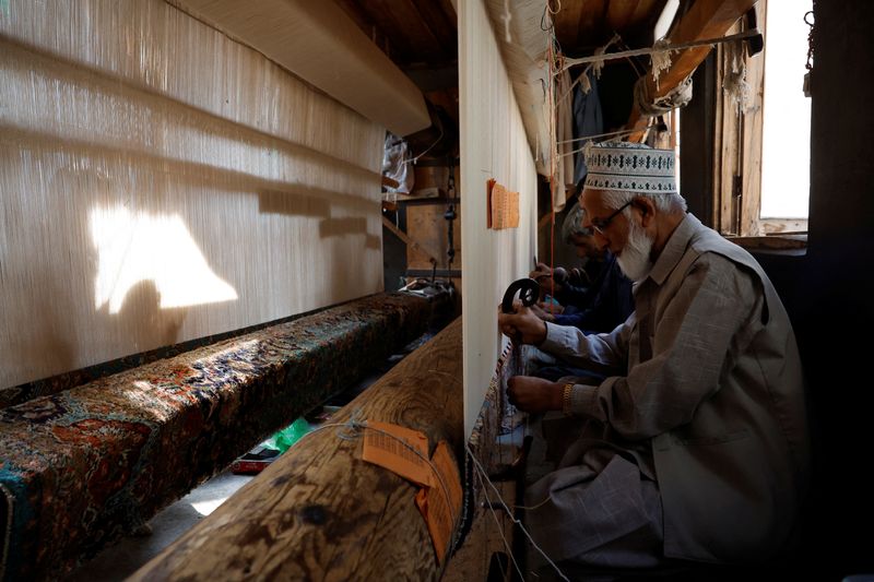Ghulam Qadir, 75, an artisan, weaves a Kashmiri hand-knotted carpet along with other artisans inside a workshop in Srinagar, Indian Kashmir, October 4, 2025. REUTERS/Sharafat Ali