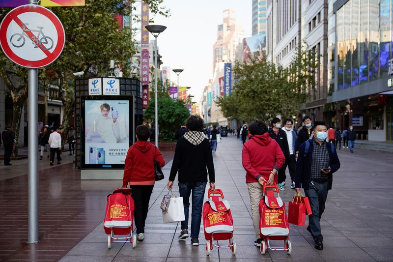 People walk with their shopping carts at a main shopping area during the Alibaba's Singles' Day shopping festival in Shanghai, China November 11, 2021. REUTERS/Aly Song
