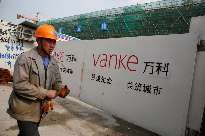 FILE PHOTO: A person walks past by a gate with a sign of Vanke at a construction site in Shanghai, China, March 21, 2017. Picture taken March 21, 2017. REUTERS/Aly Song/File Photo