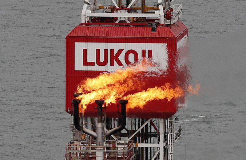 FILE PHOTO: A gas torch is seen next to the Lukoil company sign at the Filanovskogo oil platform in the Caspian Sea, Russia October 16, 2018. Picture taken October 16, 2018. REUTERS/Maxim Shemetov//File Photo