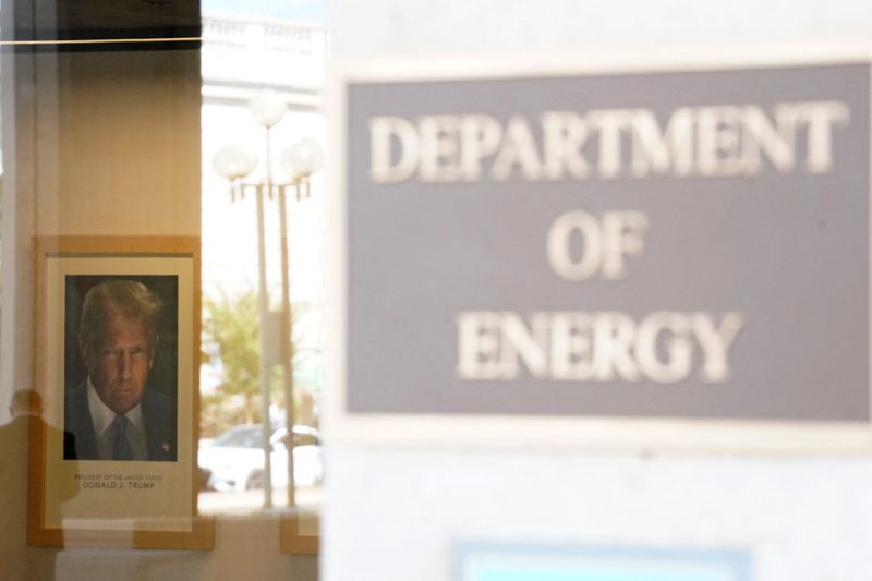 A person reflects in the window of the U.S. Department of Energy, with the official portrait of U.S. President Donald Trump on the wall, following a partial government shutdown in Washington, D.C., U.S., October 2, 2025. REUTERS/Nathan Howard