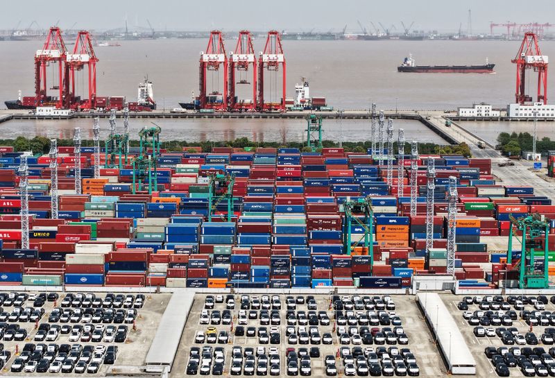 A drone view shows electric vehicles (EV) for export and containers sitting at a port in Shanghai, China April 13, 2025. China Daily via REUTERS