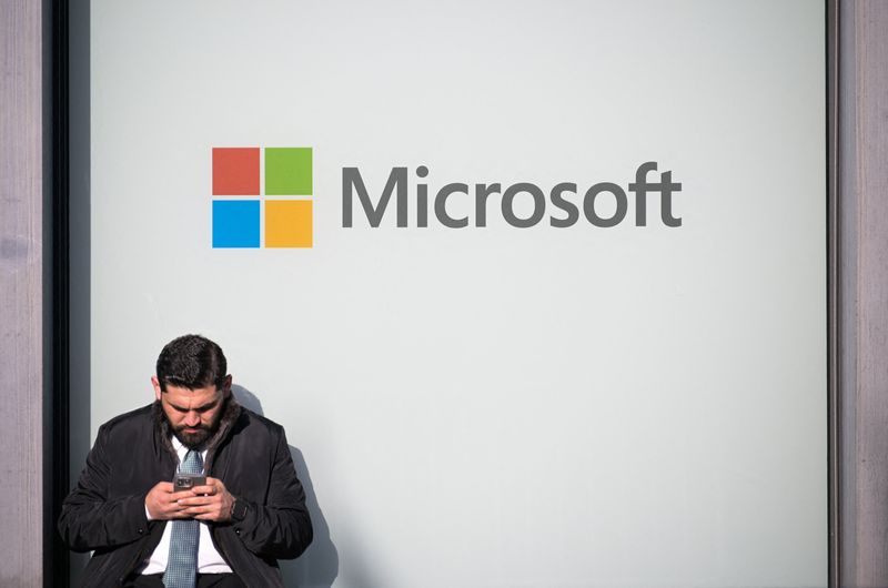 A man uses a phone next to a Microsoft logo during the 56th annual World Economic Forum (WEF) meeting, in Davos, Switzerland, January 20, 2026. REUTERS/Romina Amato