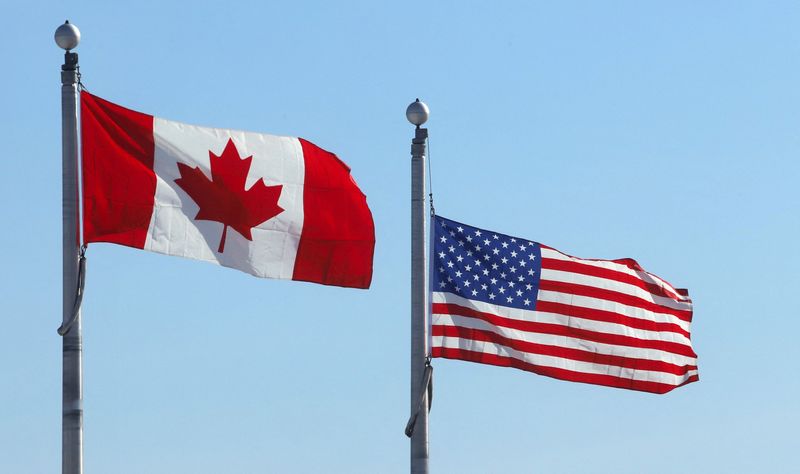 The Canadian and U.S. flags flutter at the Lansdowne Port of Entry next to the Thousand Islands Bridge in Lansdowne, Ontario, Canada February 12, 2025.  REUTERS/Patrick Doyle/File Photo