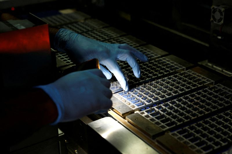 A technician checks the machine with a flashlight at a solar panel manufacturing hub in Greater Noida, on the outskirts of New Delhi India, October 23, 2024. REUTERS/Priyanshu Singh