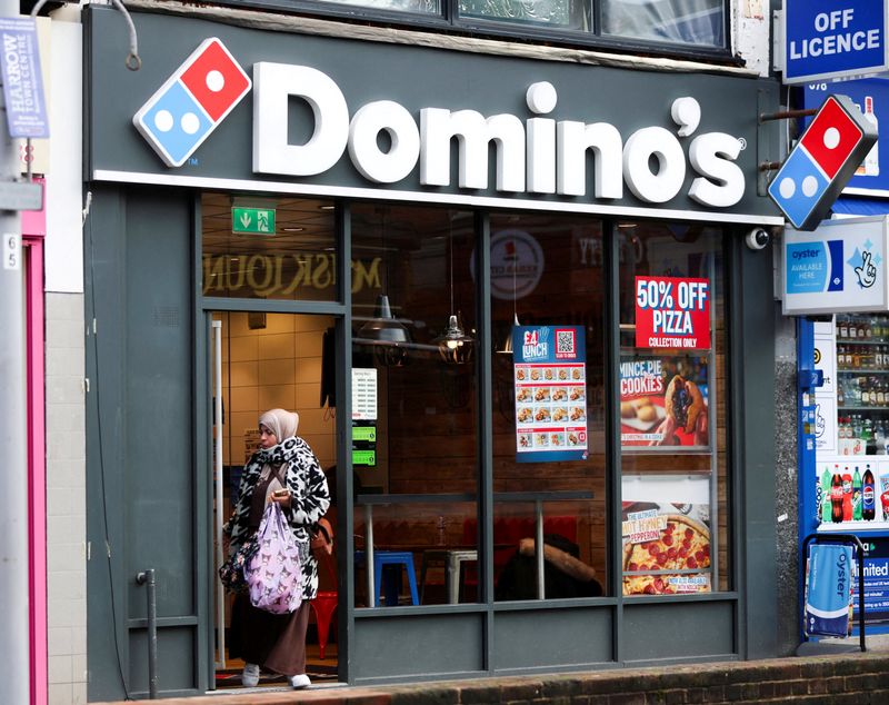FILE PHOTO: A woman leaves a branch of the Domino's Pizza franchise in London, Britain, December 5, 2025. REUTERS/Hiba Kola/File Photo