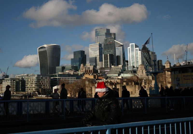 A boy wearing a Santa hat rides across Tower Bridge with the skyscrapers of the City of London business district seen behind, in London, Britain December 20, 2025. REUTERS/Isabel Infantes