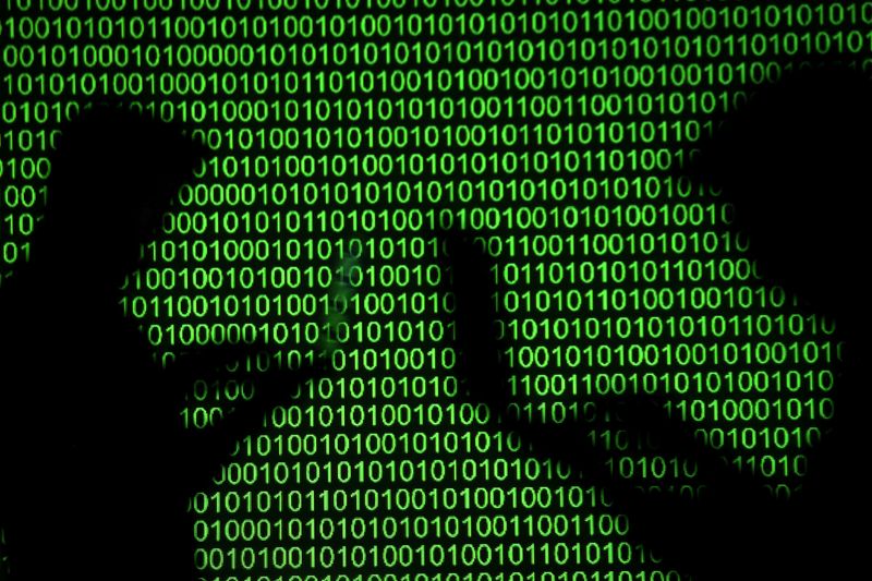 Silhouettes of laptop users are seen next to a screen projection of binary code are seen in this picture illustration taken March 28, 2018.  REUTERS/Dado Ruvic/Illustration