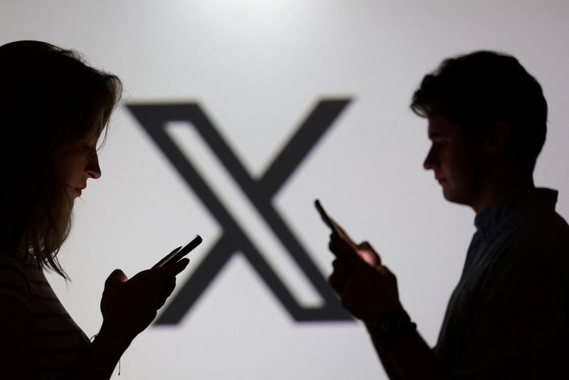 Teenagers pose for a photo while holding smartphones in front of a X logo in this illustration taken September 11, 2025. REUTERS/Dado Ruvic/Illustration