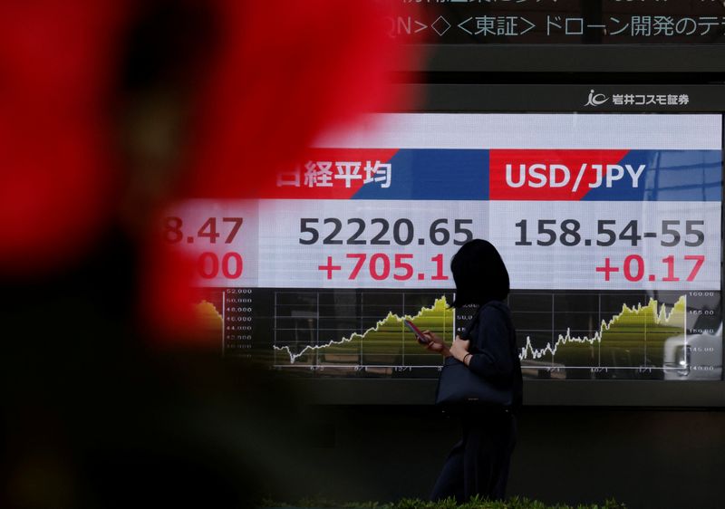A pedestrian walks past a stock quotation board showing the Nikkei share average and the exchange rate between the U.S. dollar and Japanese Yen, outside a brokerage in Tokyo, Japan, March 24, 2026. REUTERS/Kim Kyung-Hoon