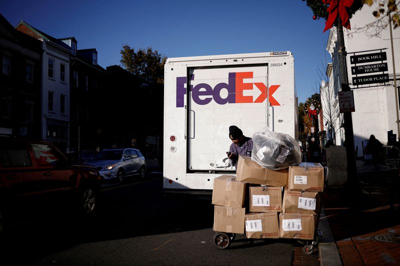 FILE PHOTO: A driver of FedEx stands with packages near a delivery truck during Black Friday preparations in the Georgetown neighborhood of Washington, U.S., November 26, 2024. REUTERS/Benoit Tessier/File Photo