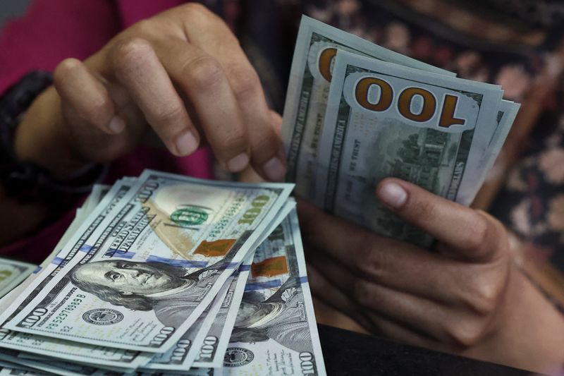 A teller counts U.S. dollar bank notes at a money changer in Jakarta, Indonesia, April 9, 2025. Picture taken through glass. REUTERS/Willy Kurniawan