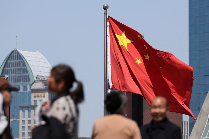 A Chinese national flag flies as people walk on a pedestrian bridge at the Lujiazui financial district in Shanghai, China April 15, 2025.  REUTERS/Go Nakamura