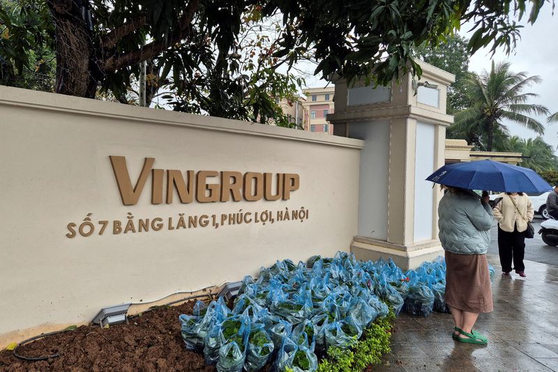 FILE PHOTO: A person with an umbrella stands near the headquarters of Vingroup, Vietnam's largest company by market capitalisation, in Hanoi, Vietnam, February 9, 2026. REUTERS/Khanh Vu/File Photo