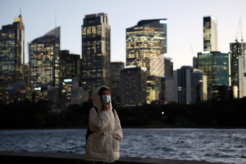 A woman walks along the waterfront at sunset in view of the Central Business District (CBD) skyline in Sydney, Australia, July 10, 2025. REUTERS/Hollie Adams